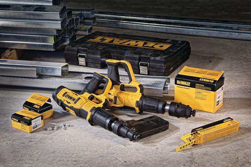 Two DEWALT yellow and black powder-actuated tools are placed on a concrete floor along with metal framing studs, a hard plastic DEWALT case, and several boxes of fasteners and cartridges used for construction work.