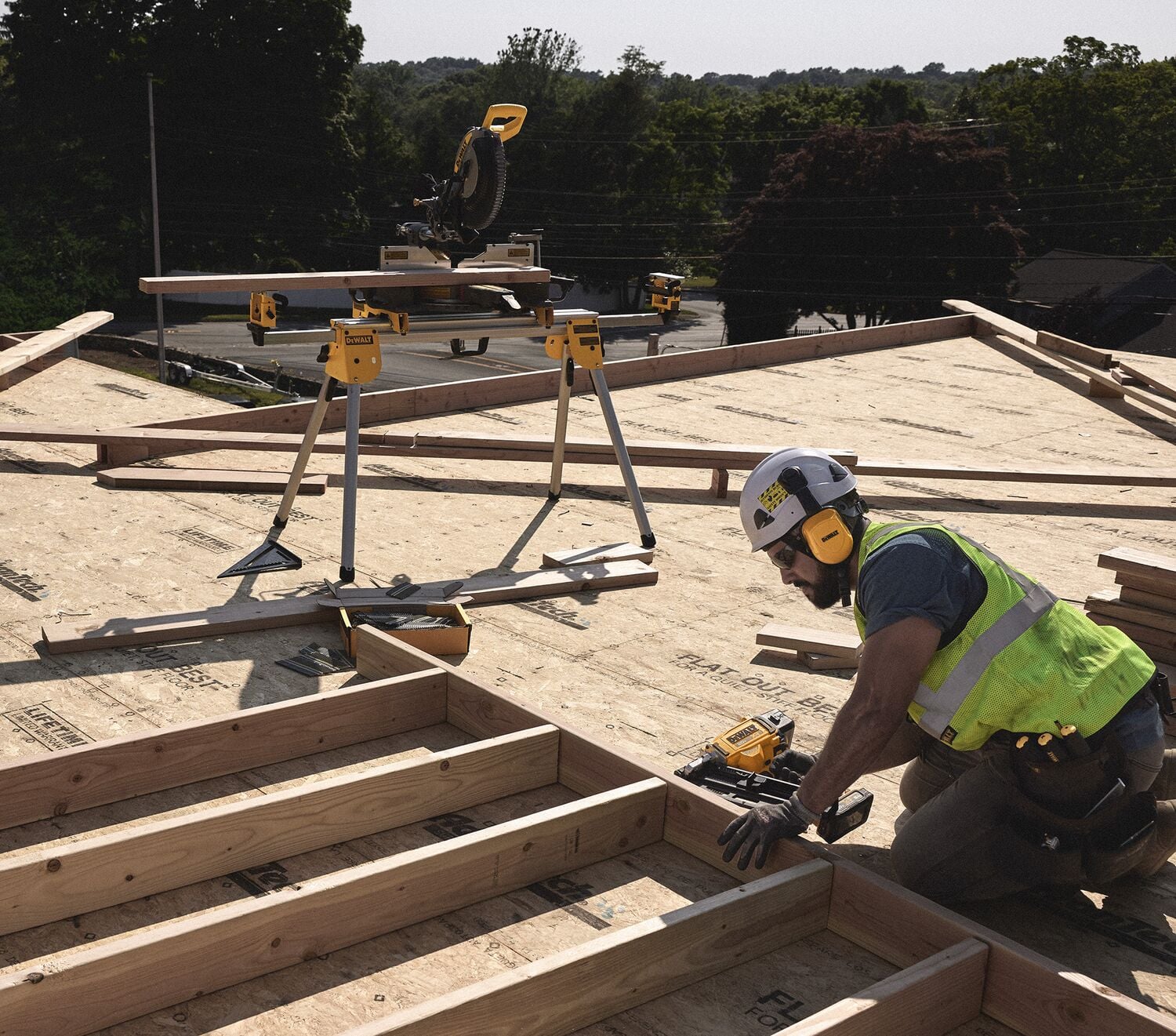 A tradesperson uses a DEWALT nailer on a frame