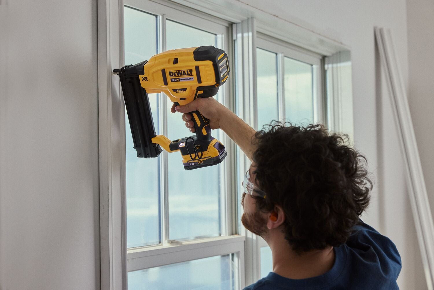 A carpenter uses a nailer on a window frame