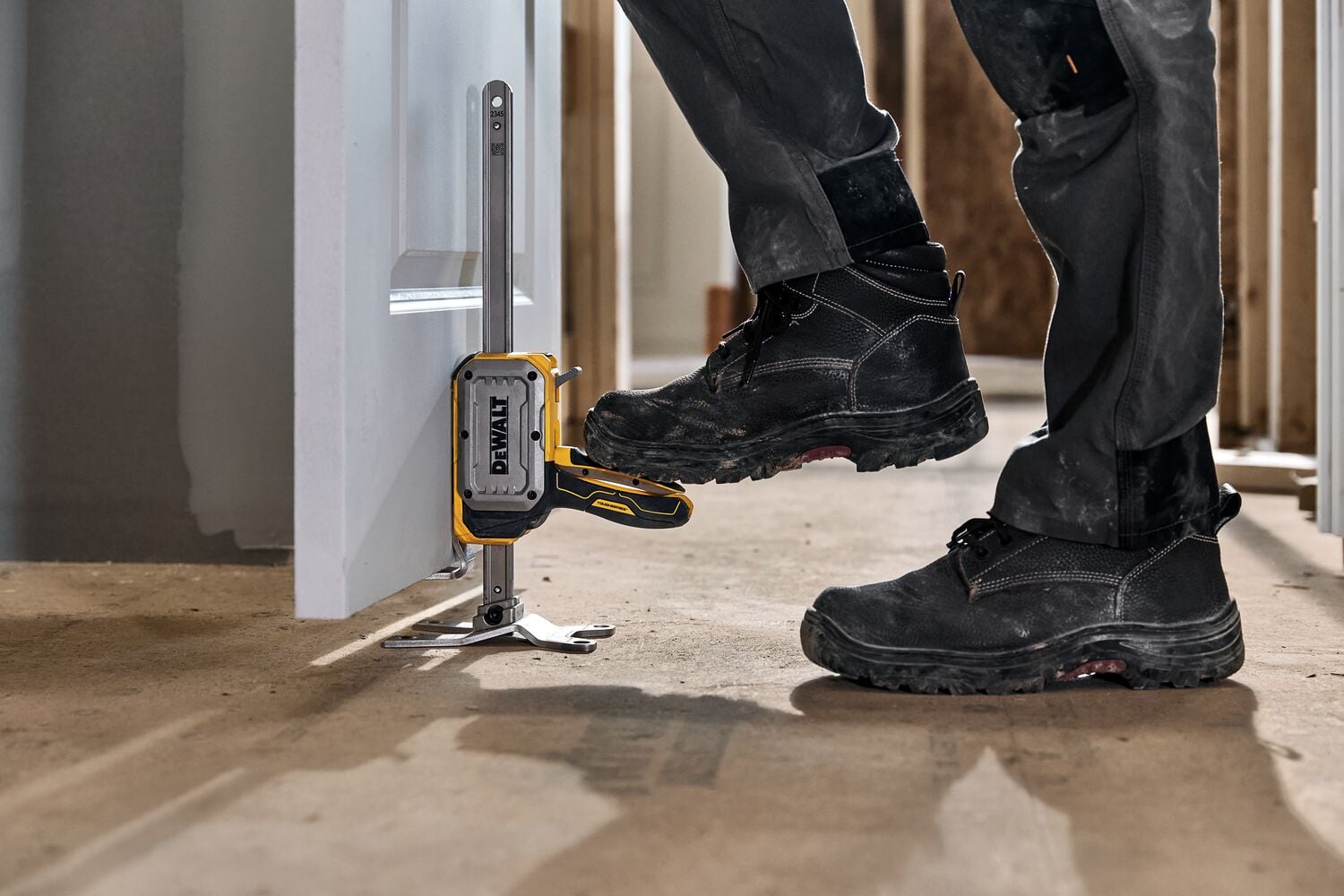 Worker lifting a door with DEWALT(R) TOUGHSERIES(TM) CONSTRUCTION JACK step to lift feature