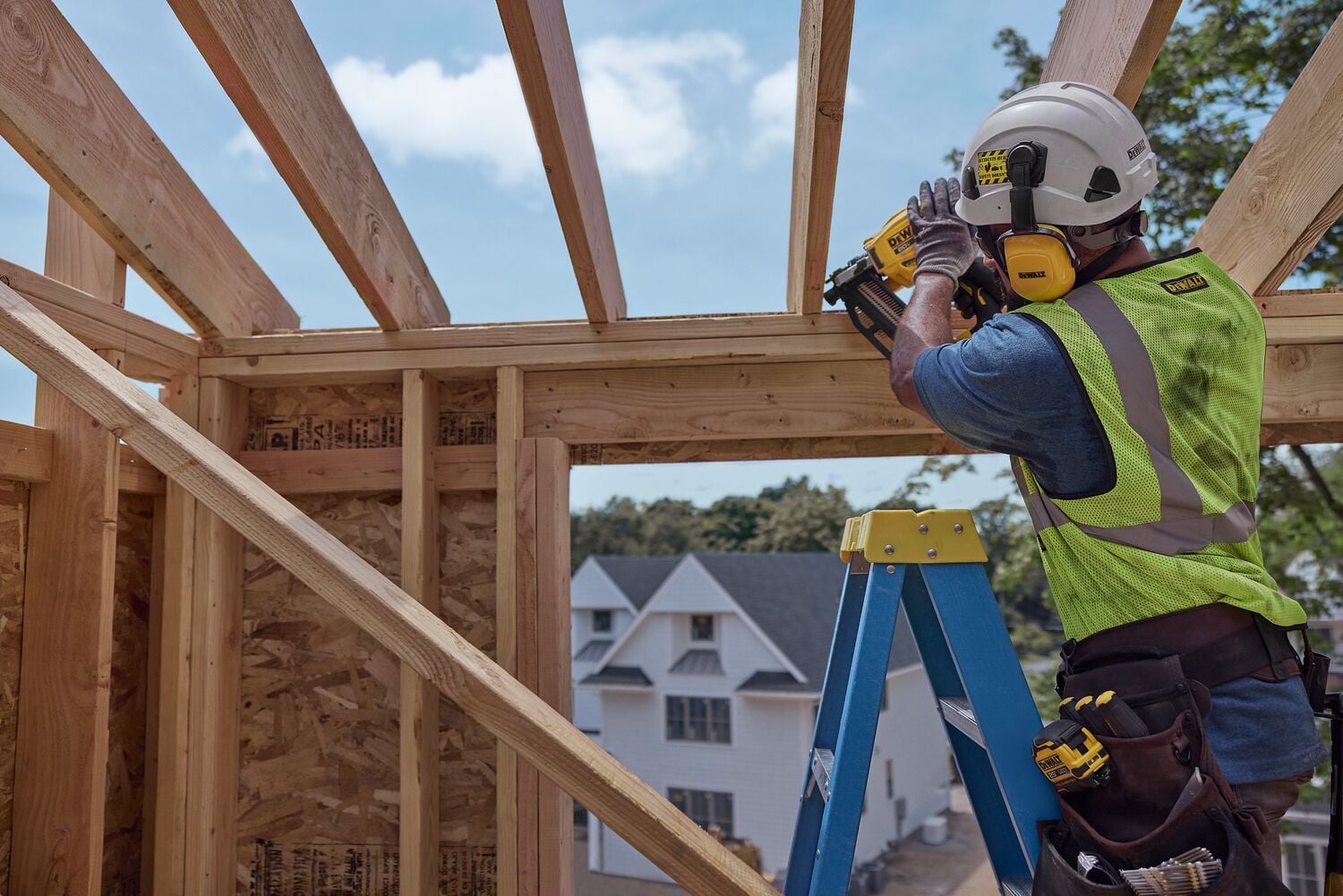 A carpenter uses a framing nailer on a frame